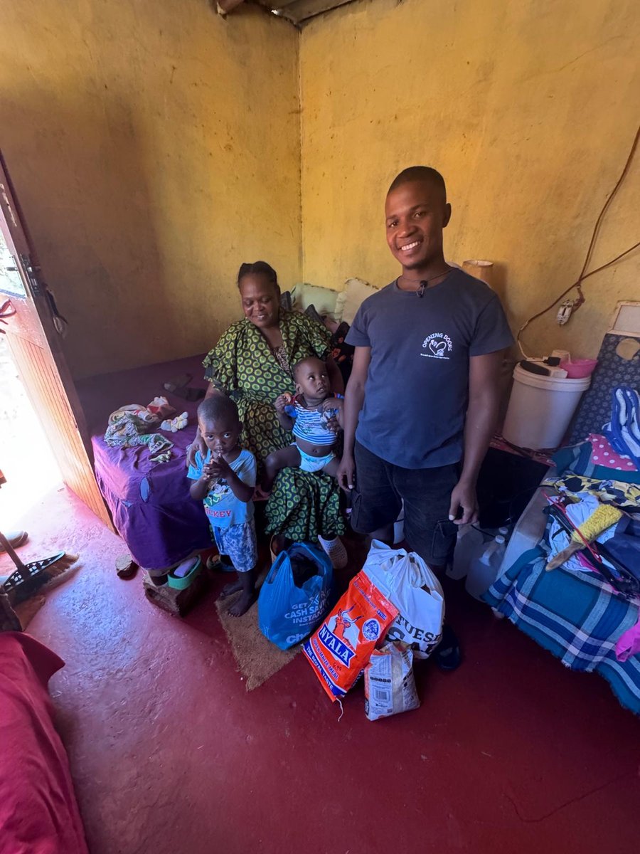 A family in their home with a food parcel delivered by an Opening Doors team member