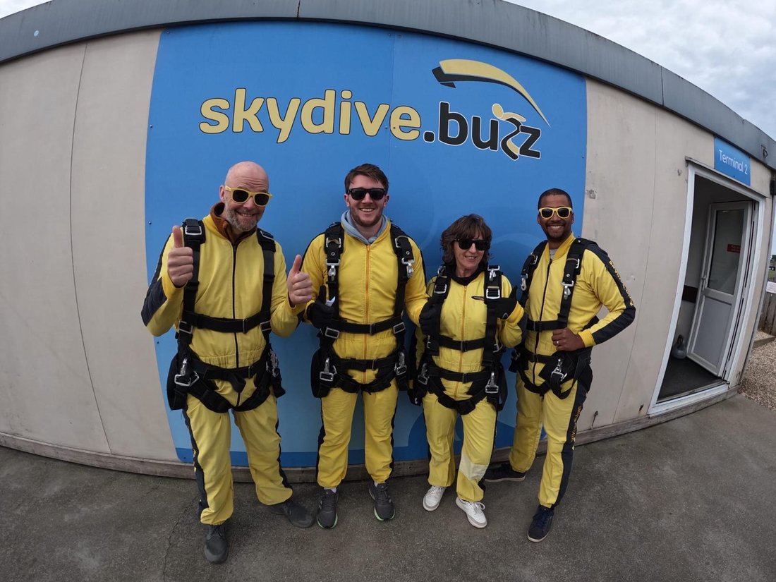 Four supporters in yellow jumpsuits, ready for the skydive they did to raise funds for Opening Doors