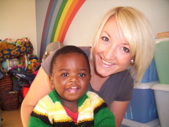 Claire with a baby called Gift while volunteering at a baby home in 2010