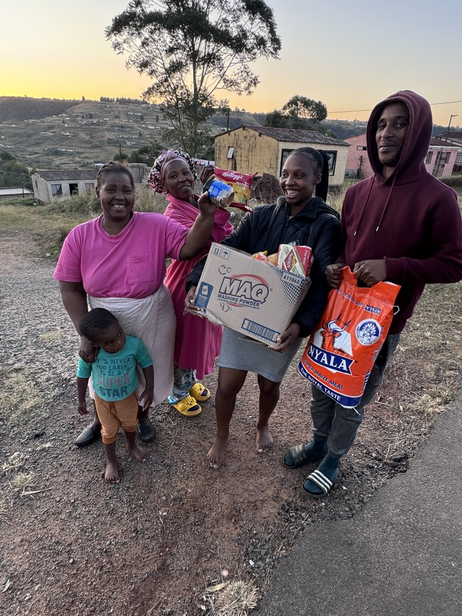 A family receiving a food parcel with maize meal, washing powder and groceries