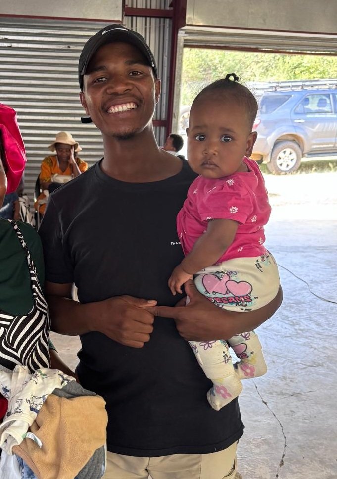 Mxolisi (aka Andrew) holding a baby from the community