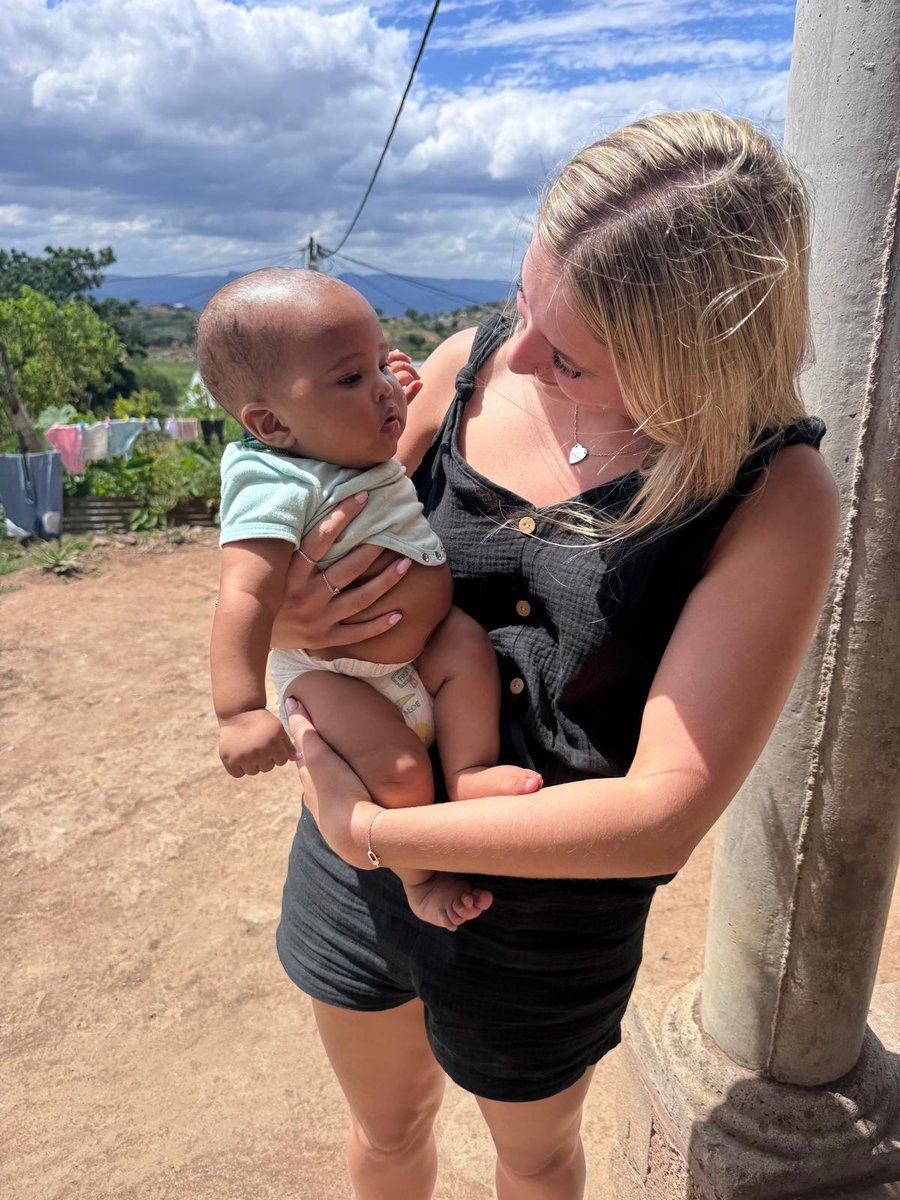 A volunteer holding a baby during a home visit