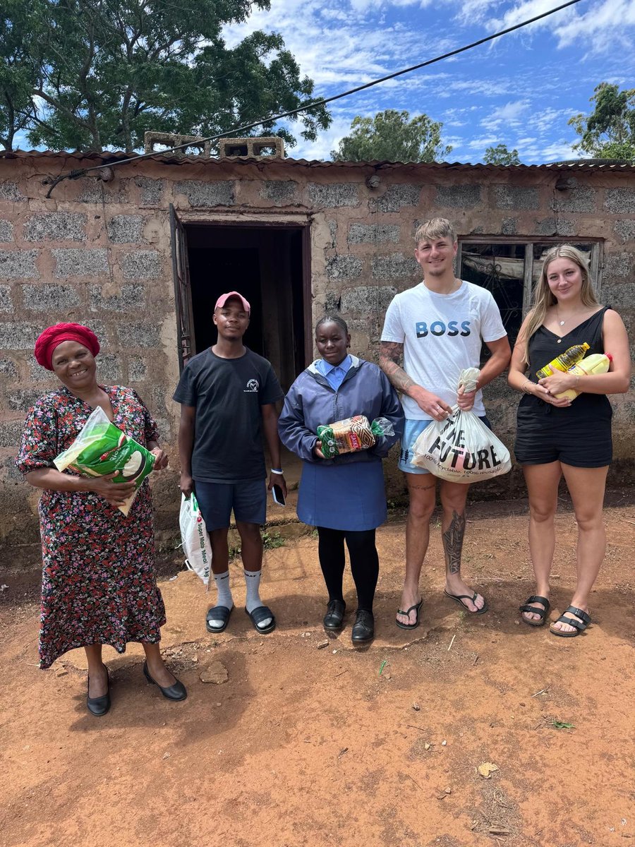Volunteers handing food parcels to a family outside their home