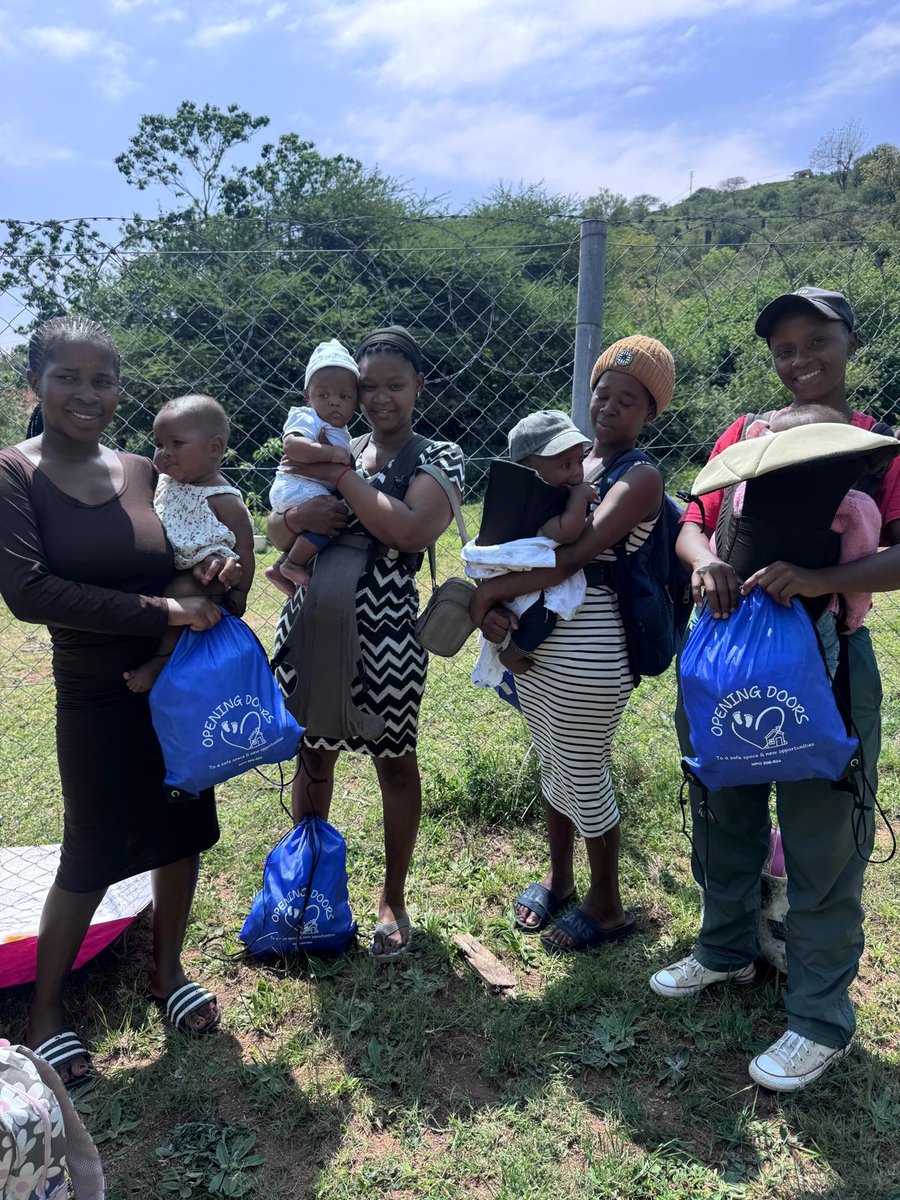 Four young mums holding their babies and their Opening Doors bags
