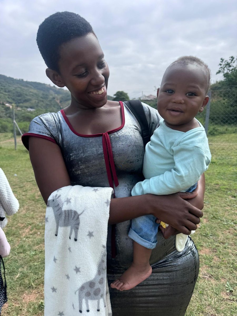 A young mum smiling at her baby, with a new zebra and giraffe blanket